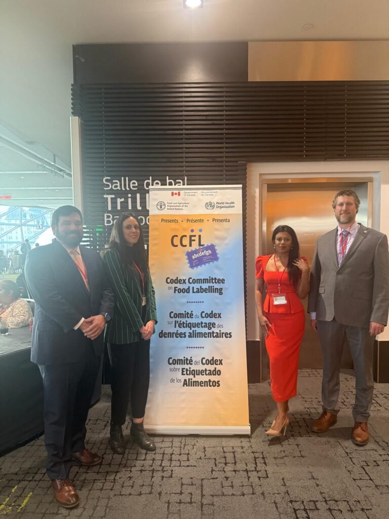 IDF representatives, including Nicholas Gardner (US), Matt Morrison (Canada), Chathurika Dayananda (Canada) and Anabel Mulet-Cabero (IDF Head Office), attending the Codex Committee on Food Labelling (CCFL49) in Ottawa, Canada, standing next to an event banner.